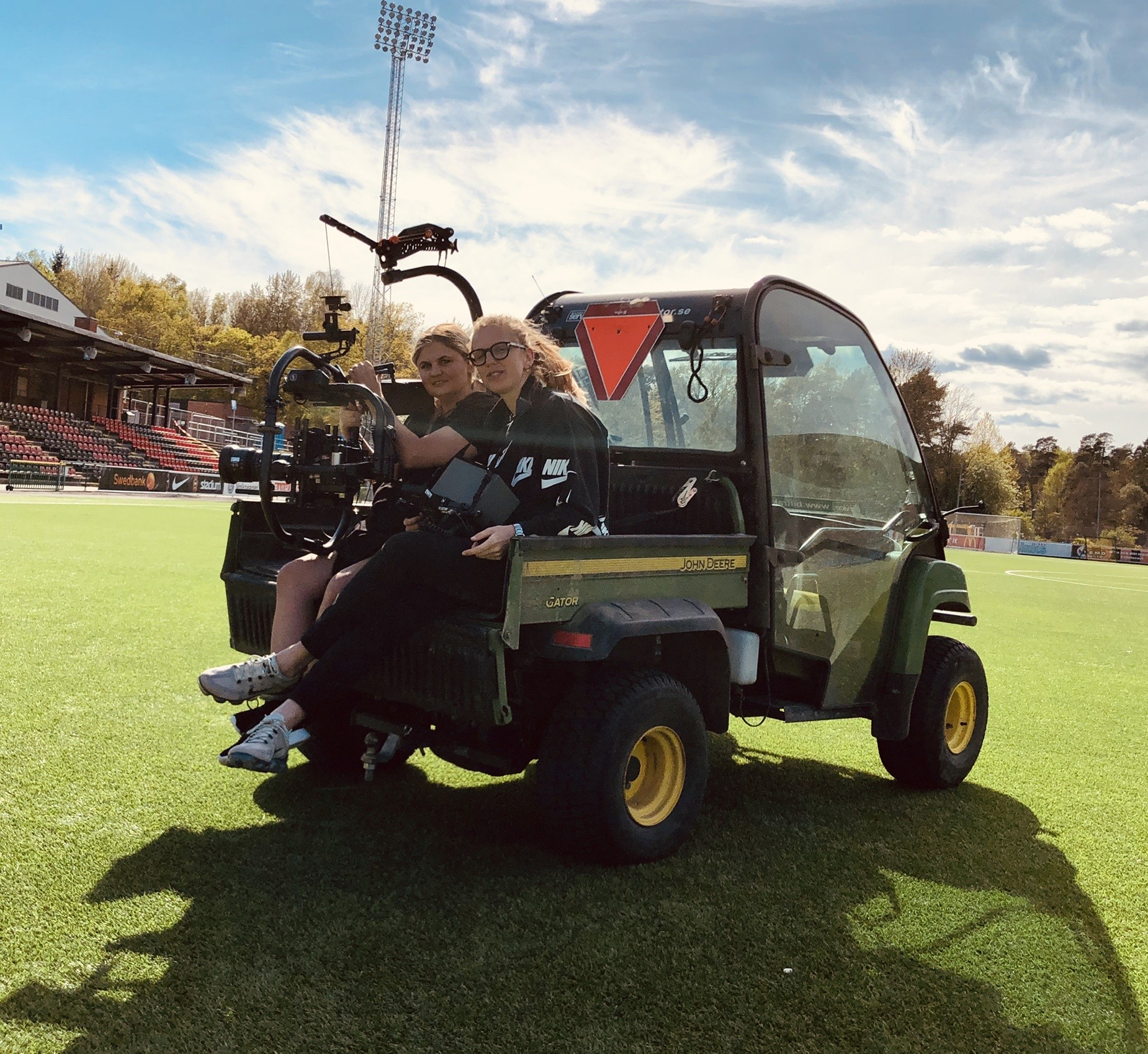 Teodora and a crew member in a buggy on set holding camera kit