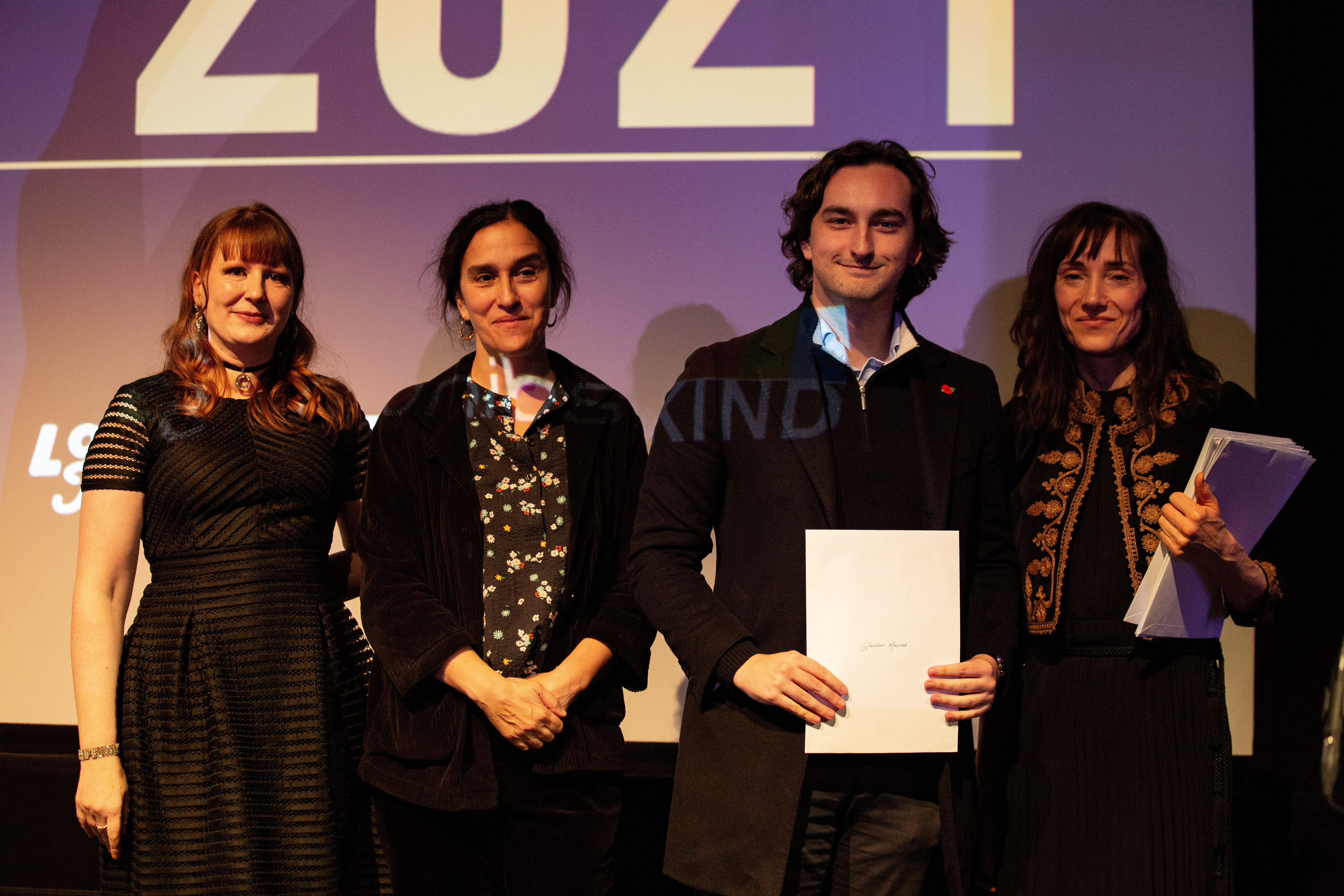 Lachlan holding his graduation certificate on stage