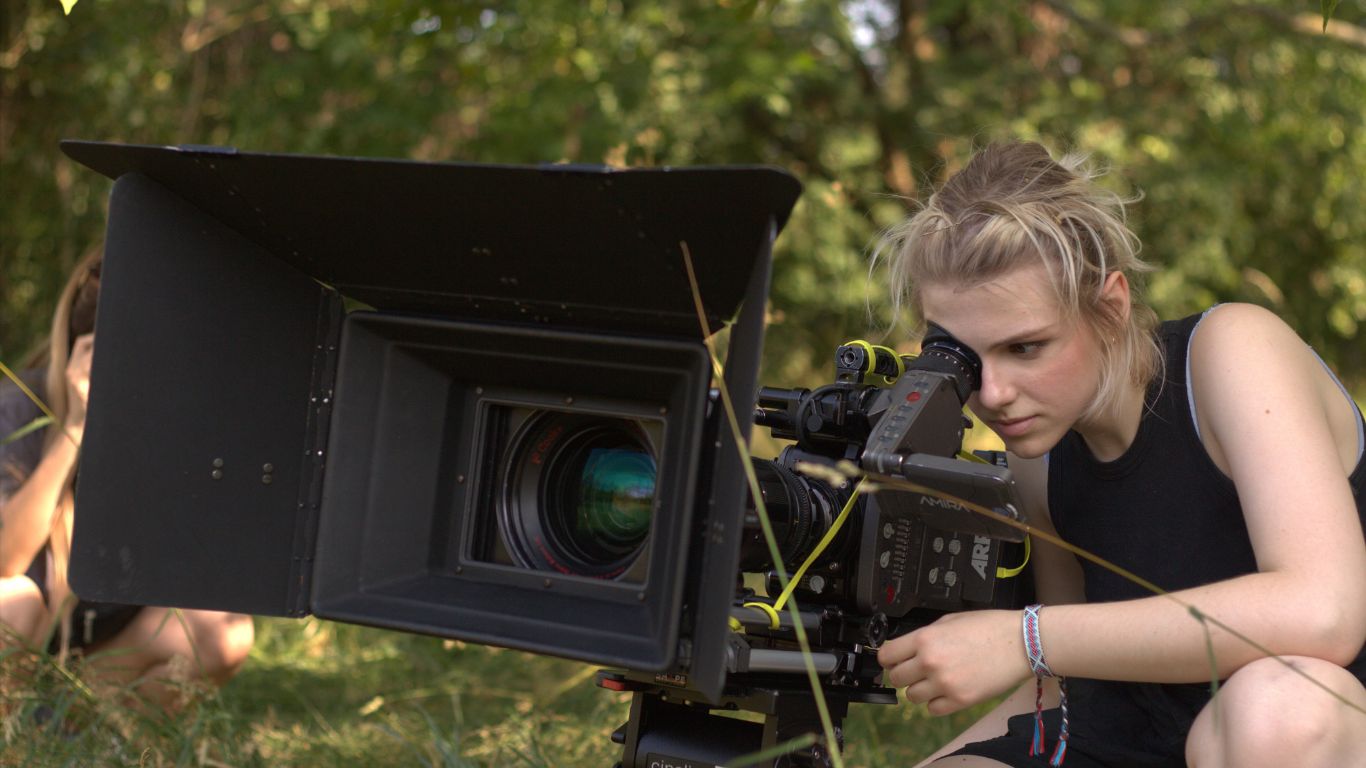 student on set with large camera operating it