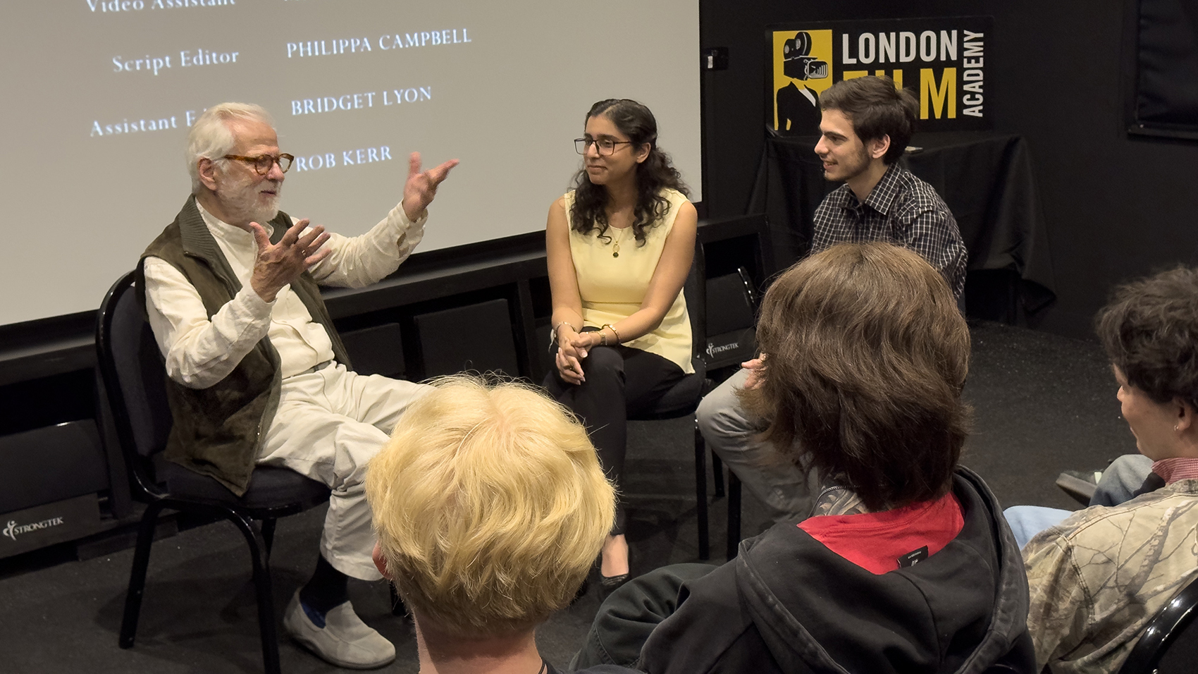 Students interviewing filmmaker in cinema