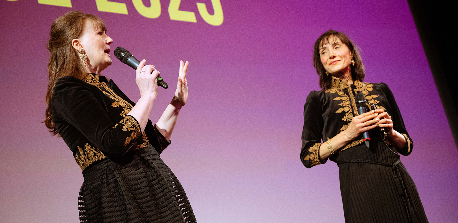 Two women onstage, giving a speech
