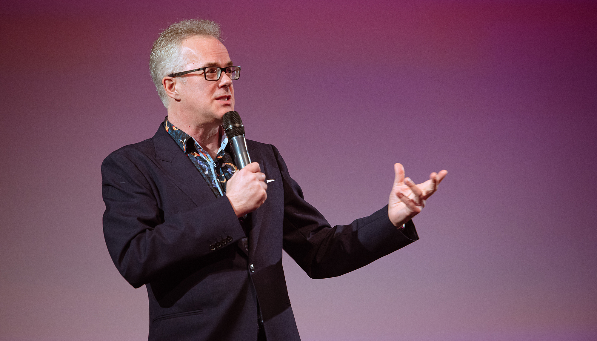 Man on stage with microphone speaking to students