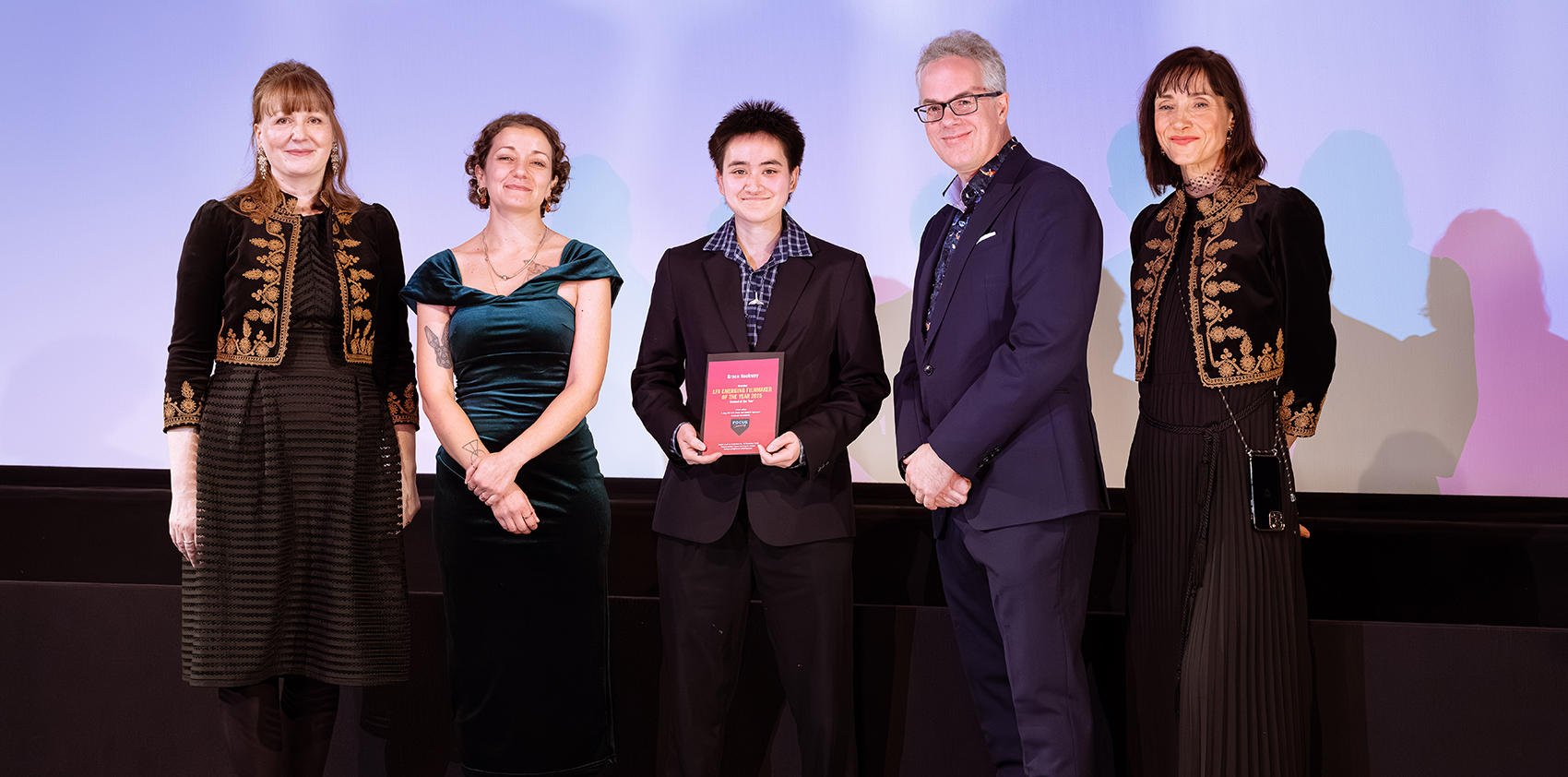 Five people onstage, smiling at camera