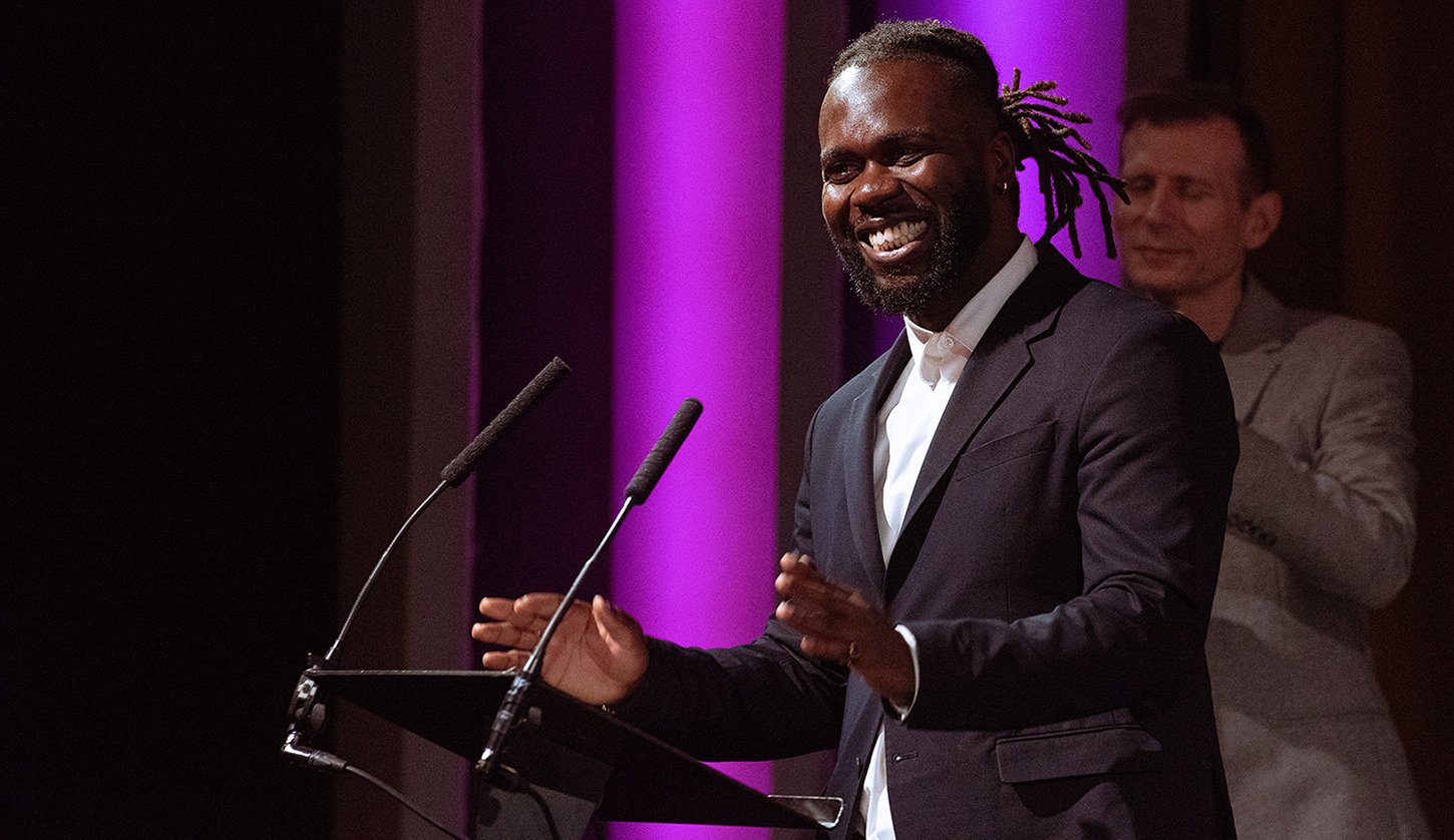 Smiling male student giving speech onstage