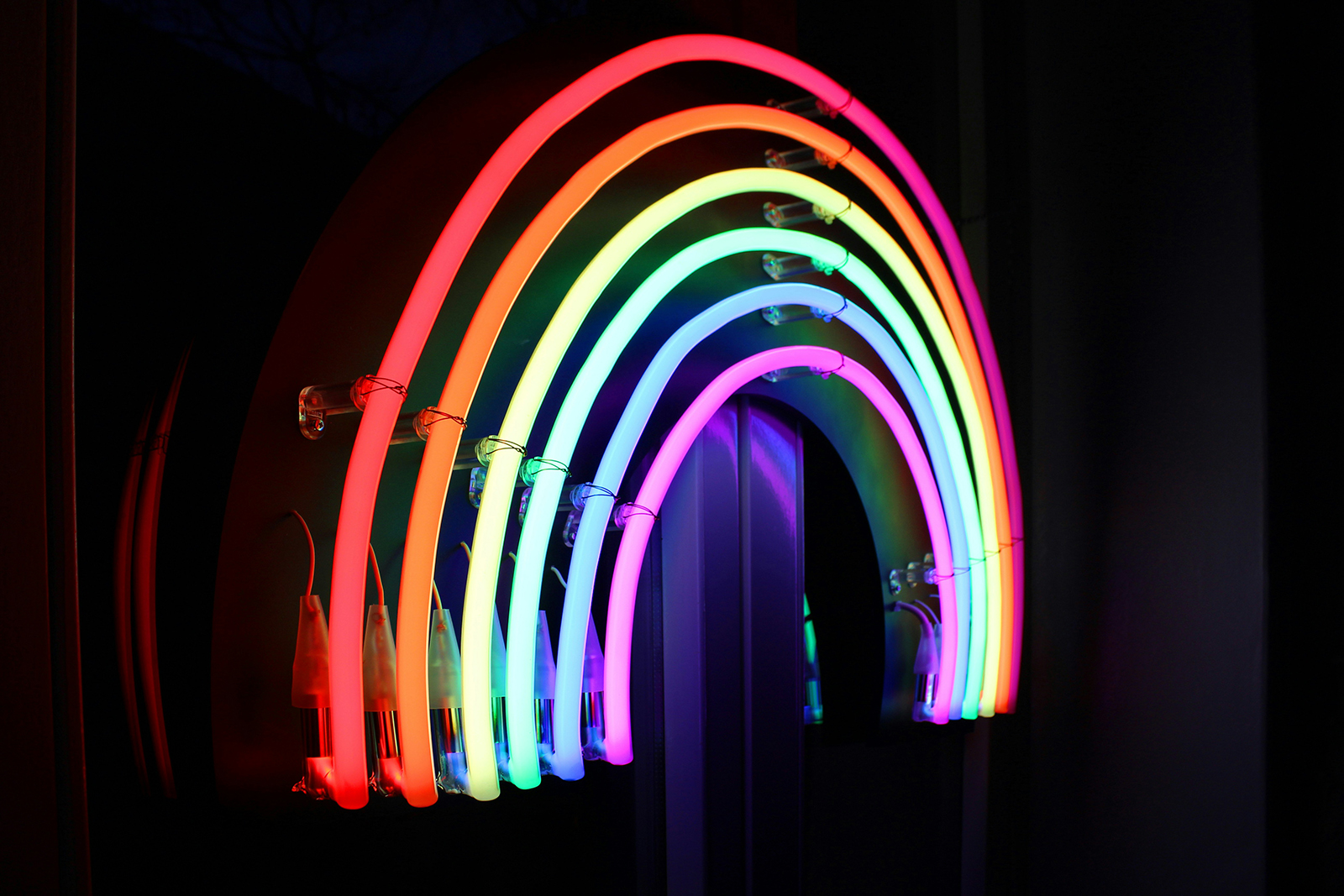 A rainbow display made of neon lights against a black backdrop