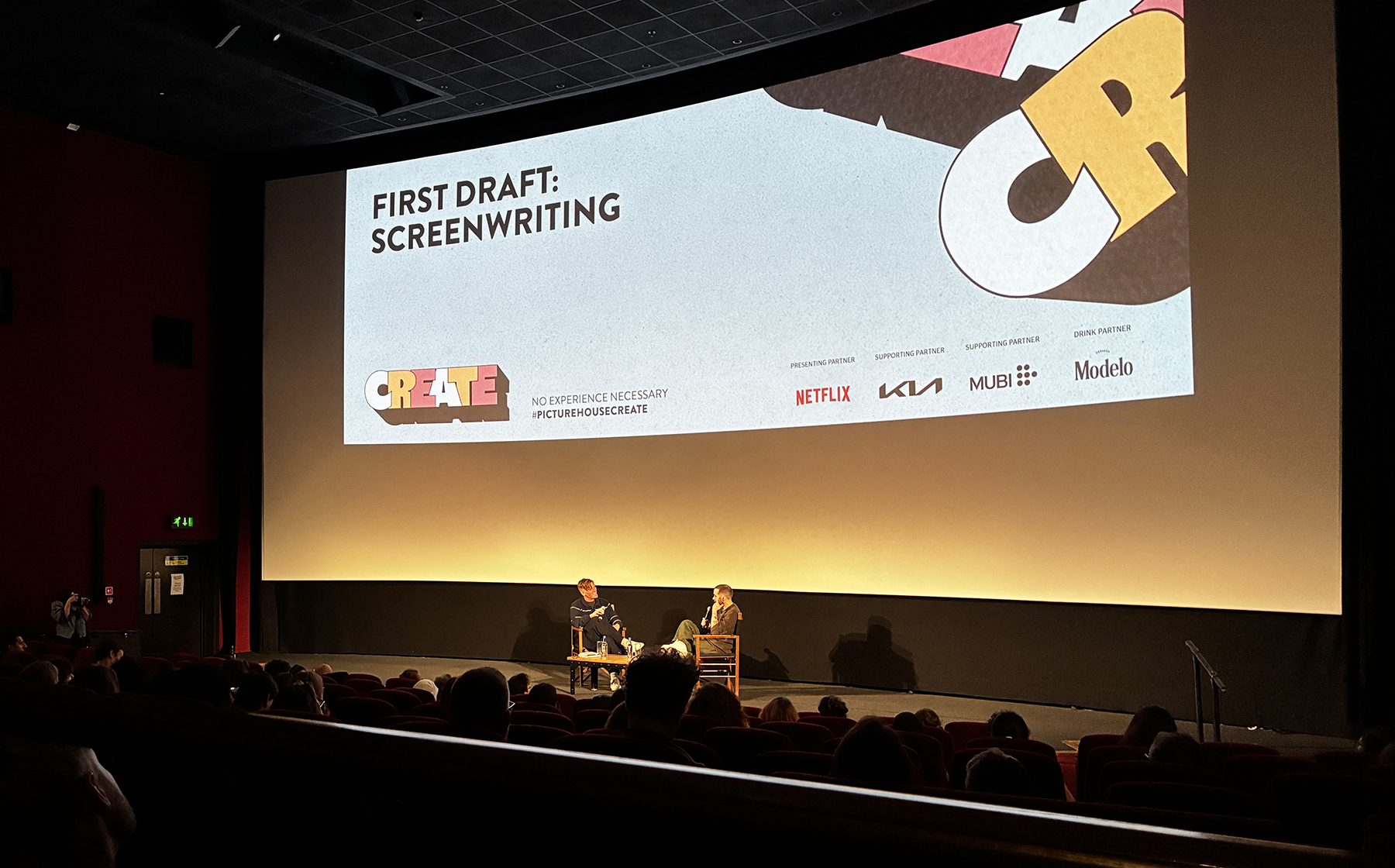 Two men sitting on stage, talking