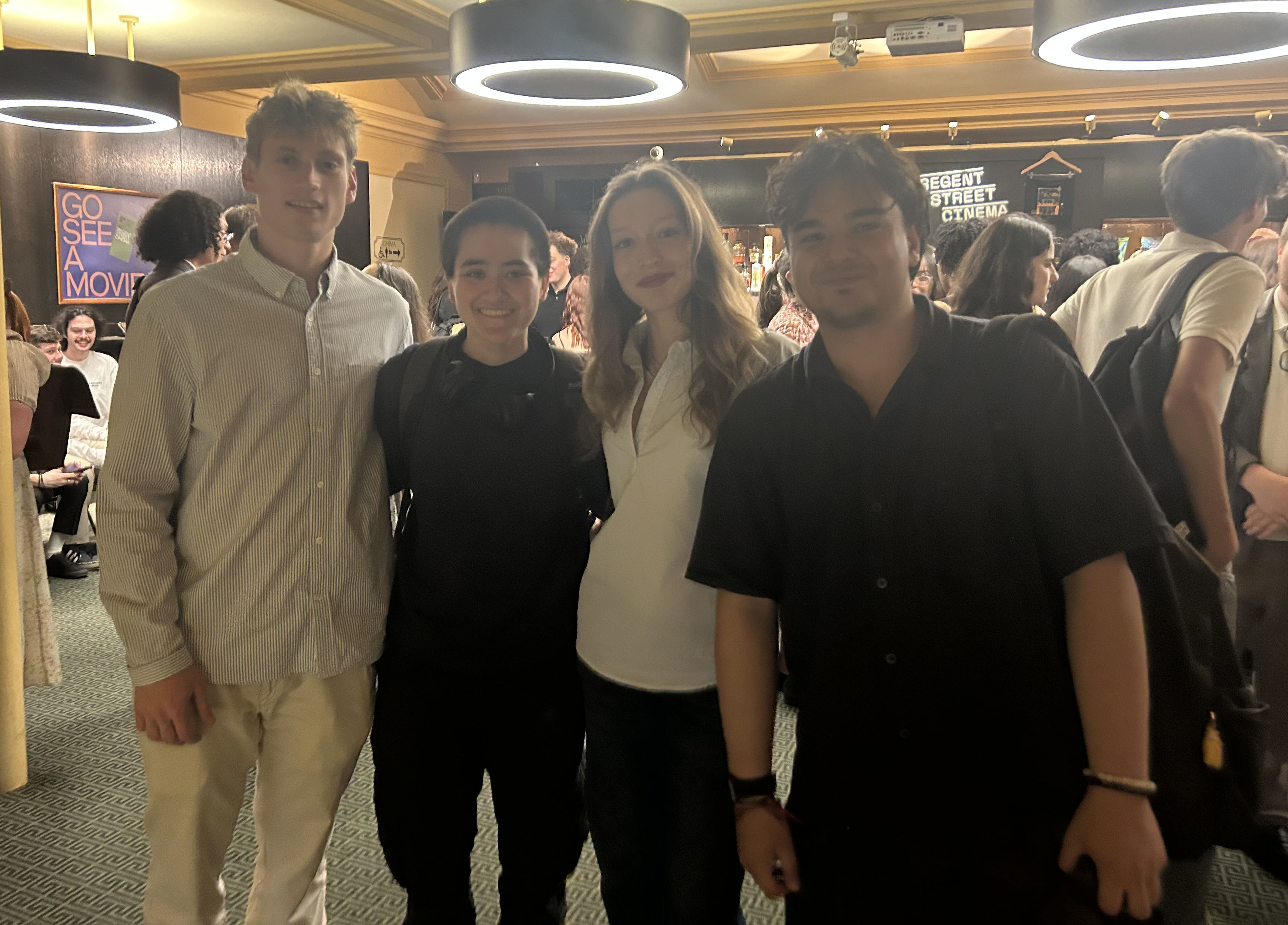 Four smiling students pose in cinema foyer before awards commence