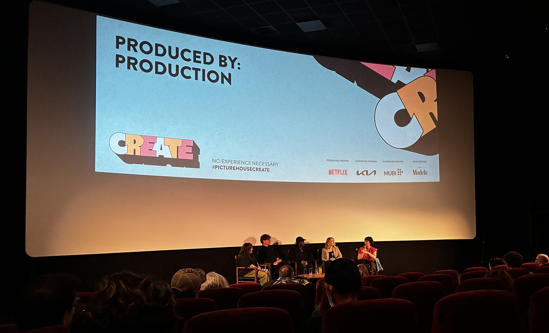Panellists talking on stage in cinema screen